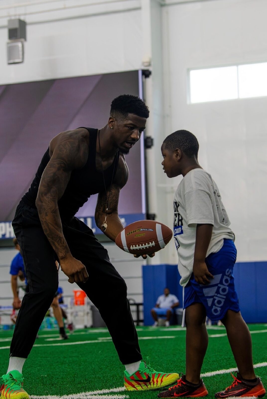 Anthony Miller II coaching a young camper one on one with a football