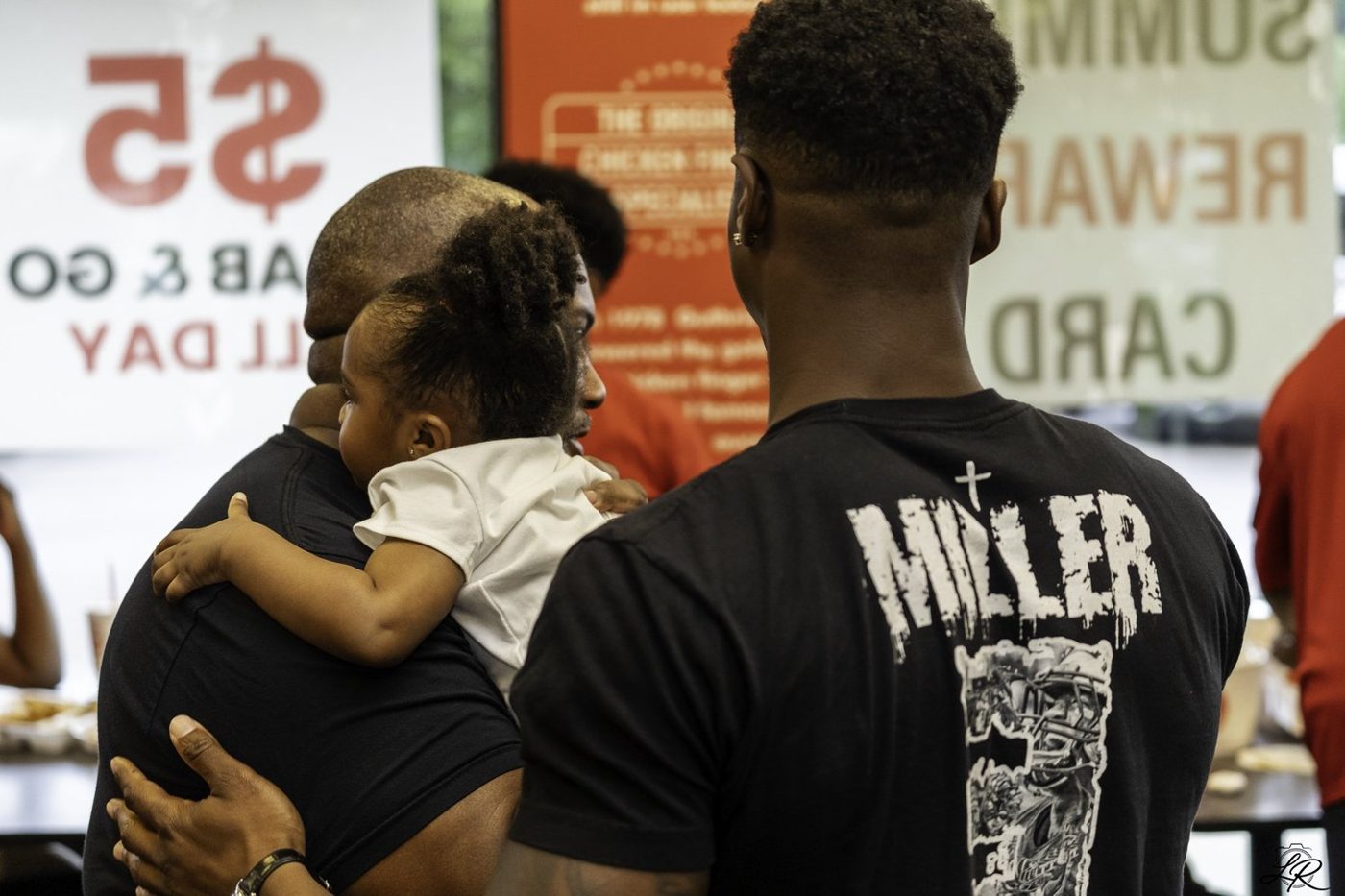 Anthony Miller holding a young child at the community signing